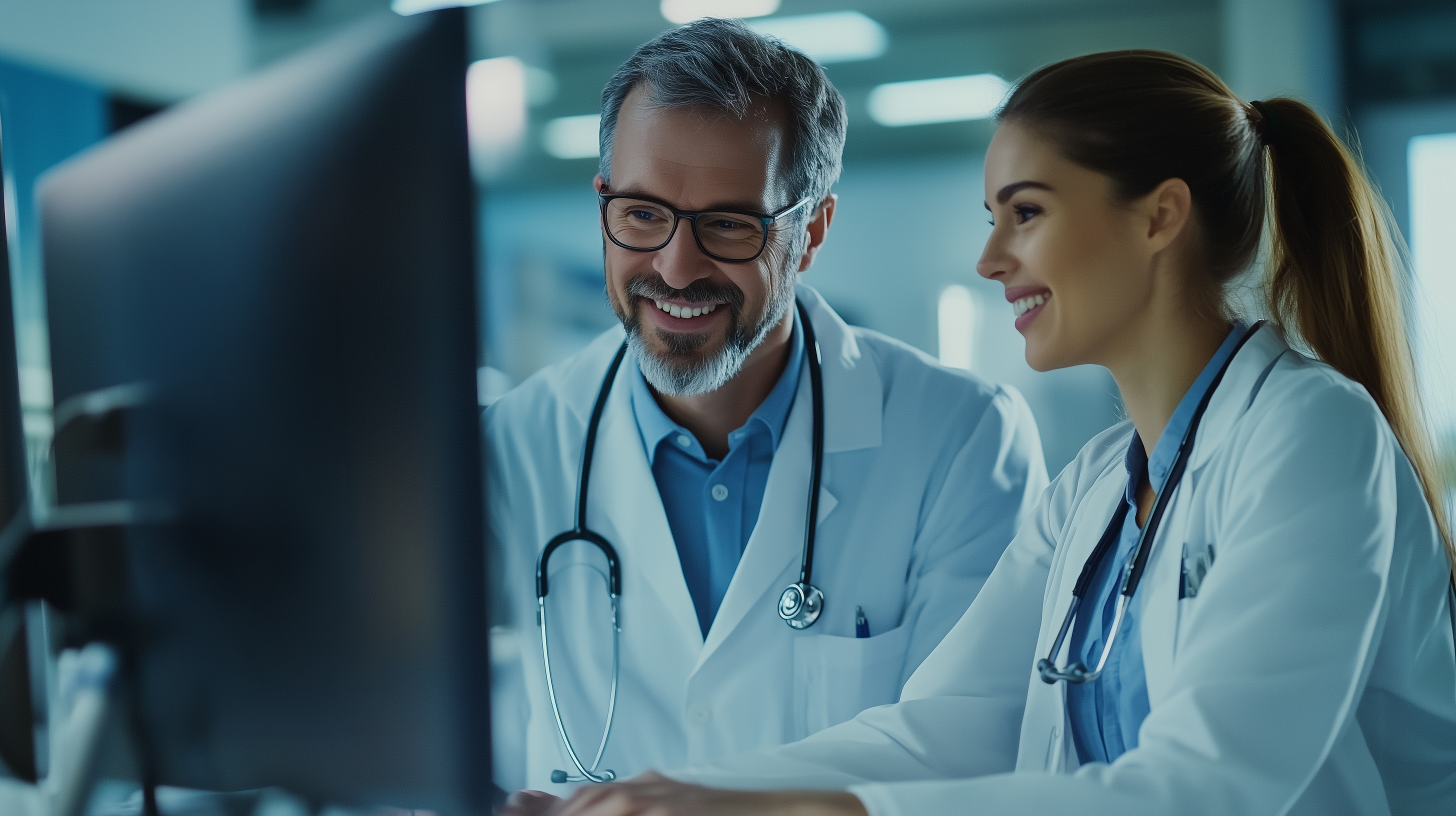 A male and a female doctor standing together and looking at a computer screen